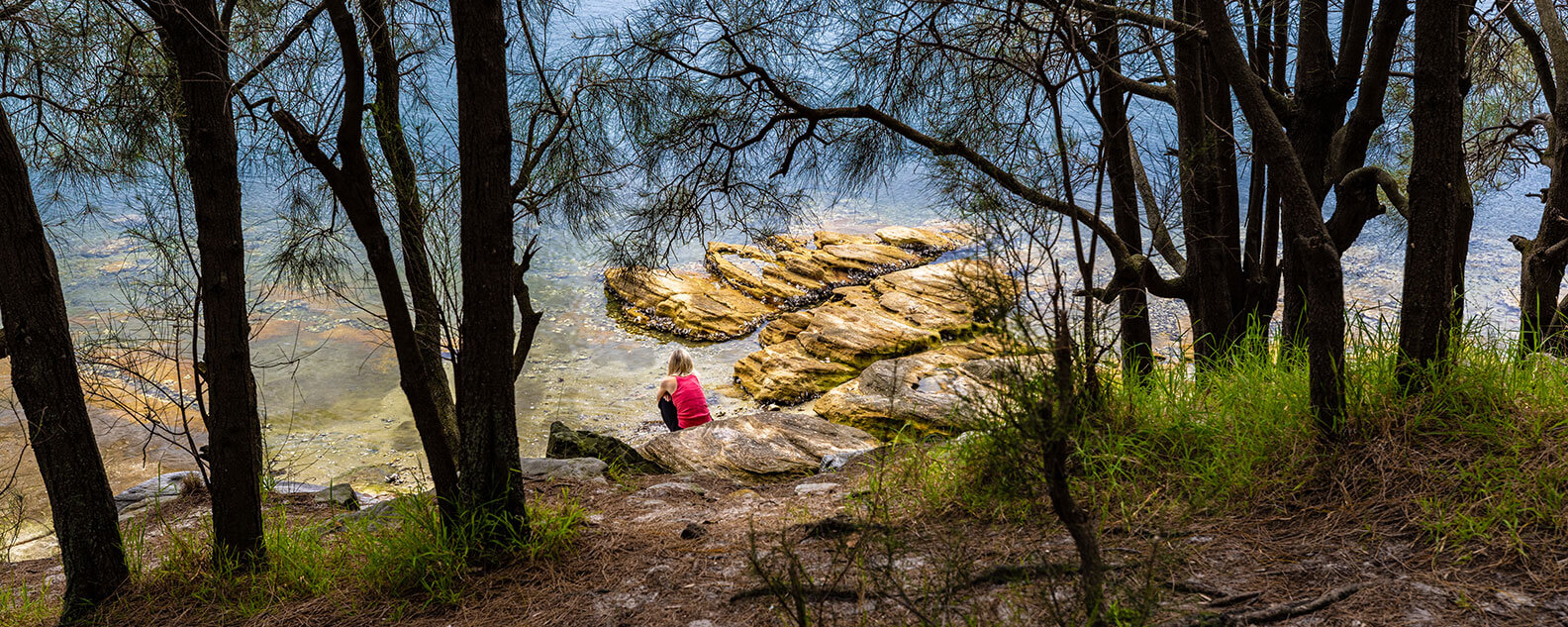 Woman sitting on rocks beside lake in park