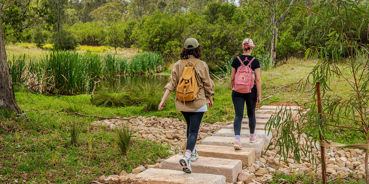 Two women walking down path in bushland