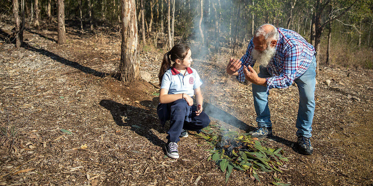 Indigenous park ranger showing tree type to student in bushland