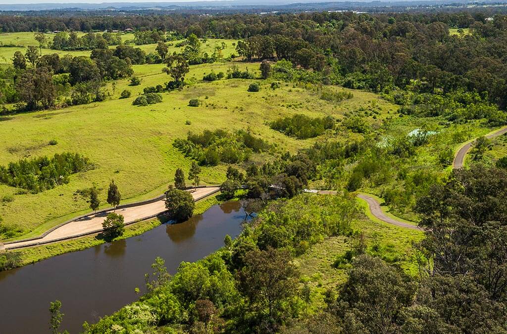 Aerial view of a water body surrounded by lush green grass in the Shale Hills region.