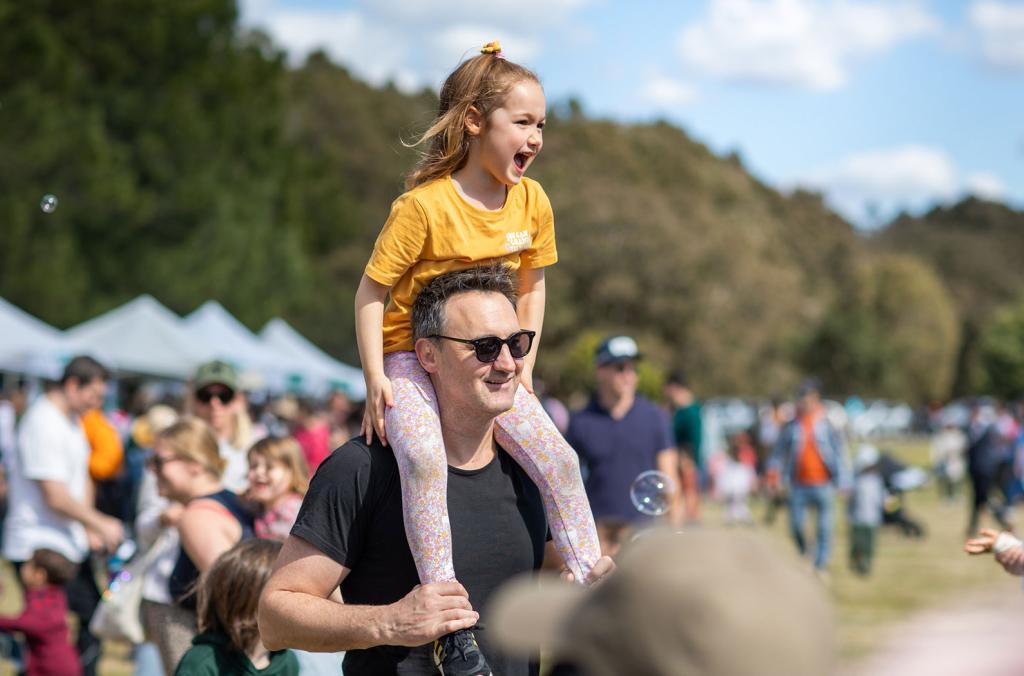 Child sitting on father's shoulders at festival