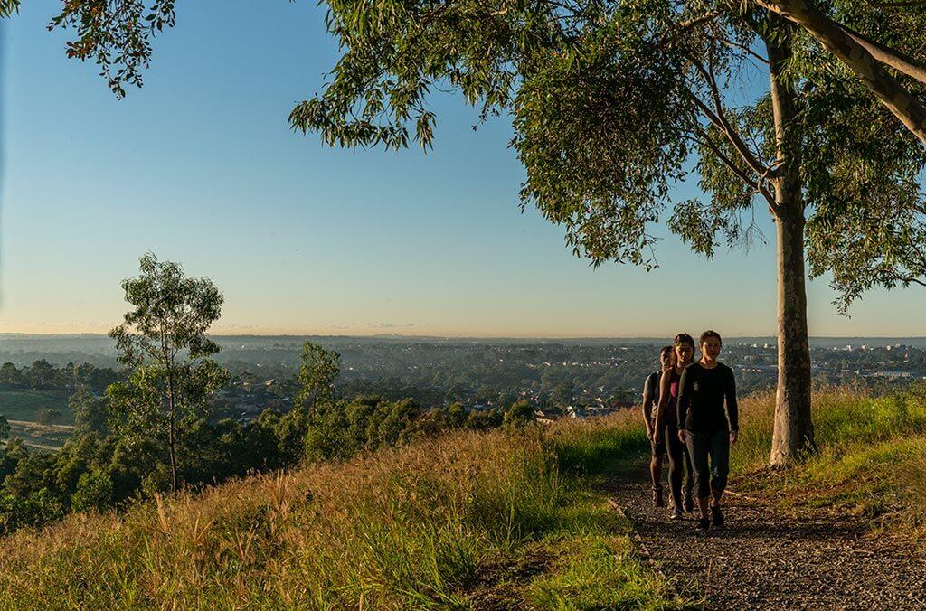 A scenic view of three hikers walking on a path surrounded by trees on the Moonrise Loop trail.
