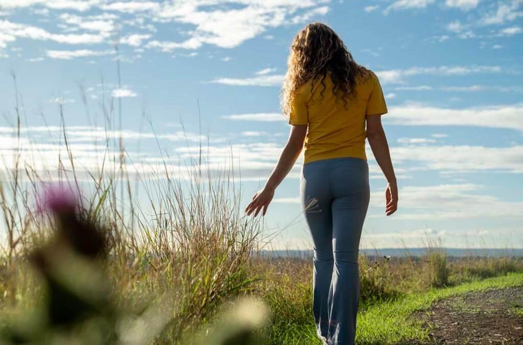 A woman strolls along a grassy path on the Moonrise loop.