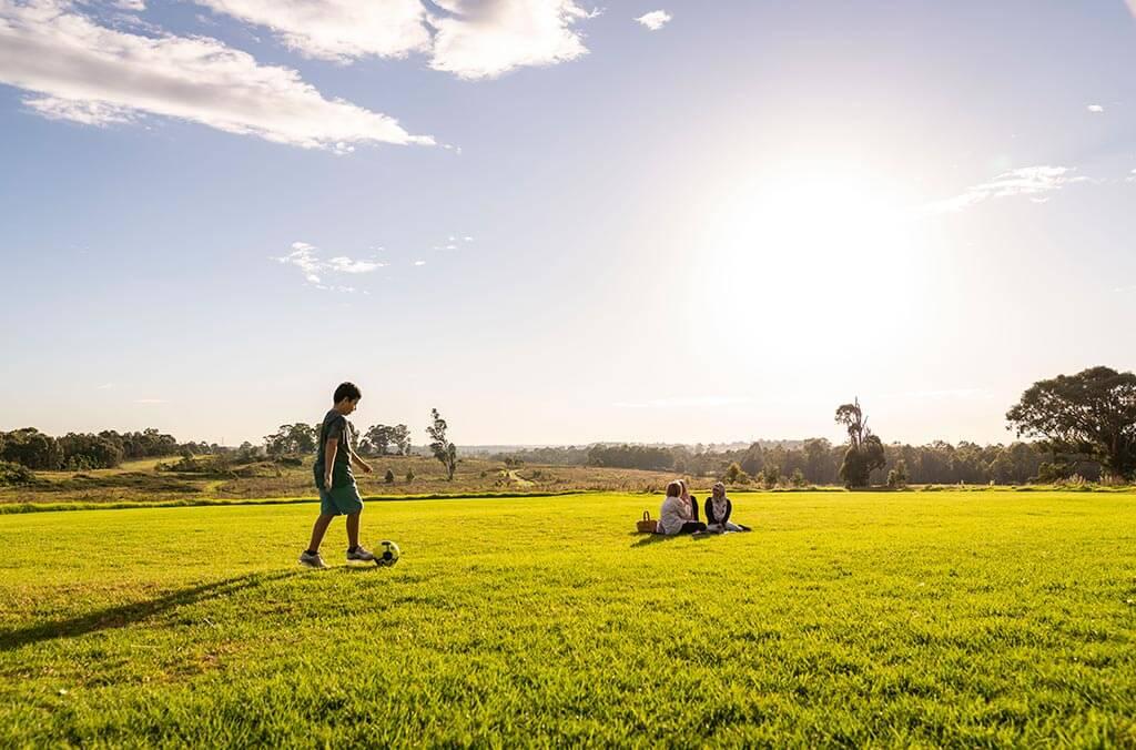 A boy plays soccer in a grassy field at Plough and Harrow Loop.