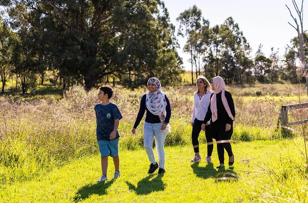 Three women and a boy stroll through a grassy field on the Plough and Harrow Loop.