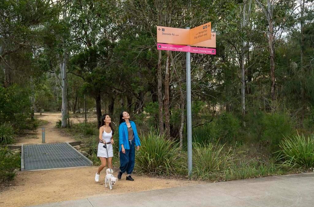 Two people stroll with their dog beneath the Shale Hills Loop sign.