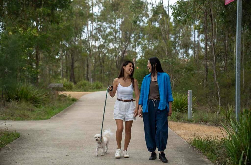 Two women walk their dog together on a path at Shale Hills Loop.