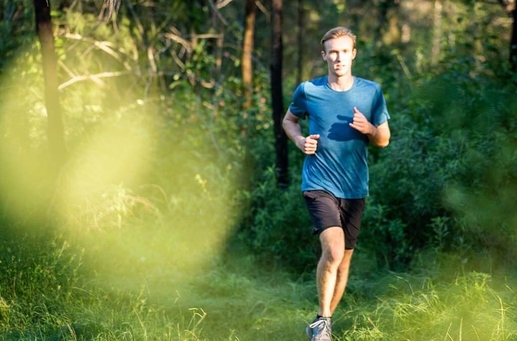 A man runs through the Spotted Gums Trail, surrounded by tall trees.