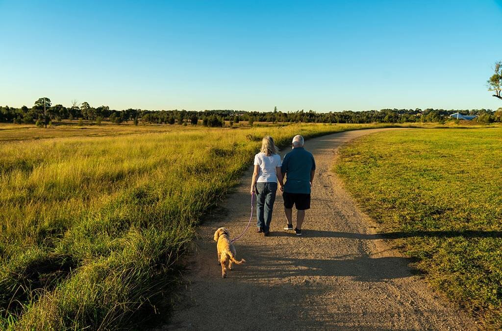 A couple strolls with their dog on a path at Heart Crossing Loop.