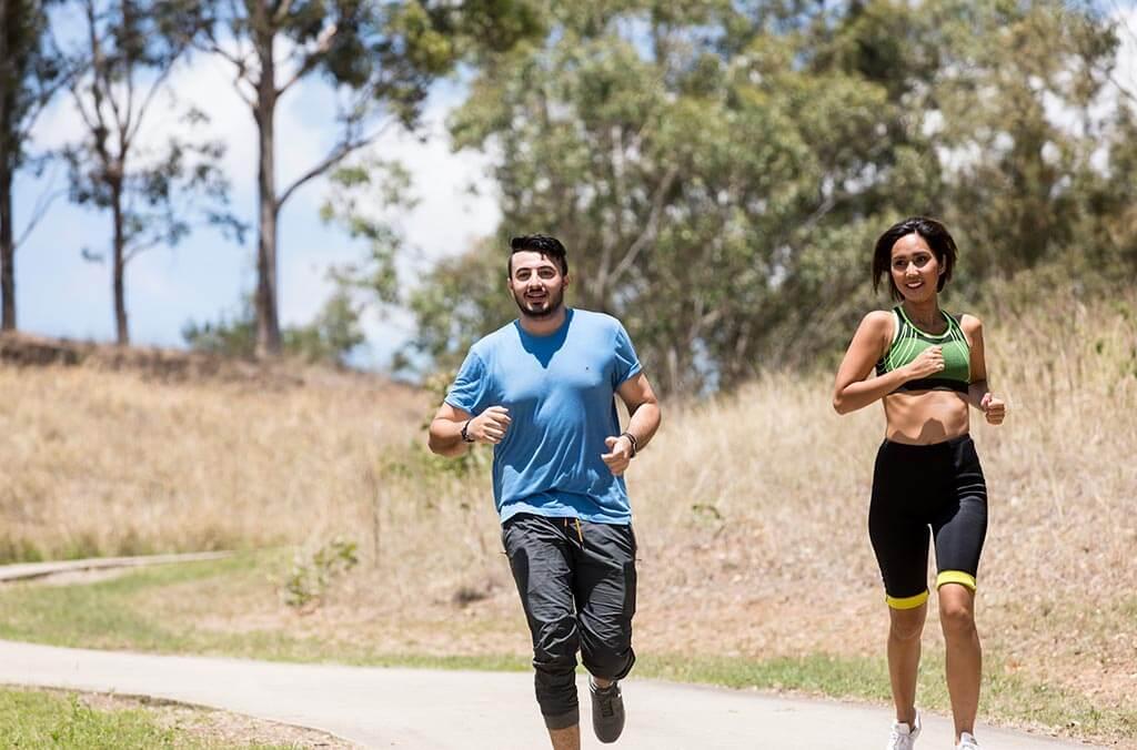 A man and woman run side by side on the Sugarloaf loop, enjoying a sunny day.
