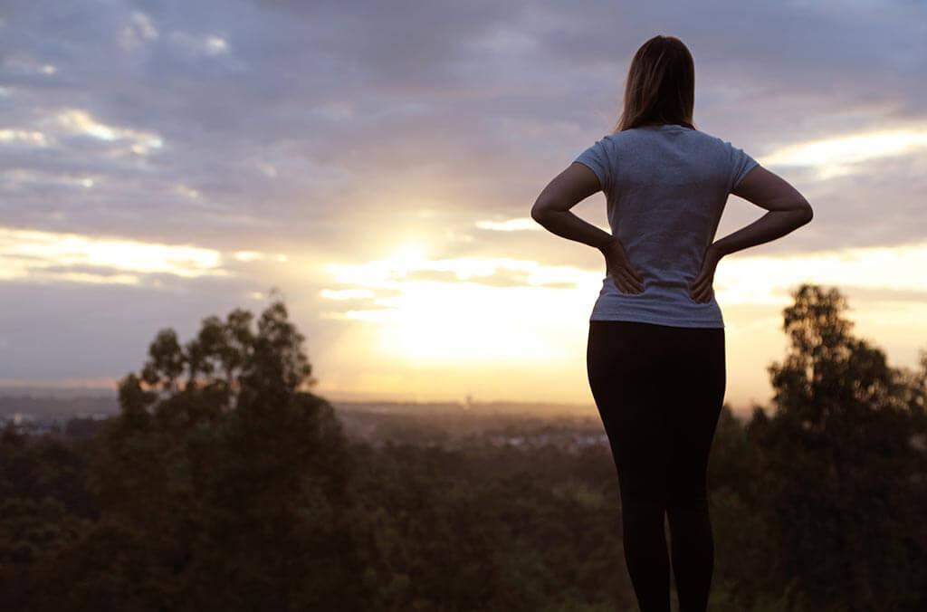 At Sugarloaf Loop, a woman enjoys a stunning sunset view from a hilltop.